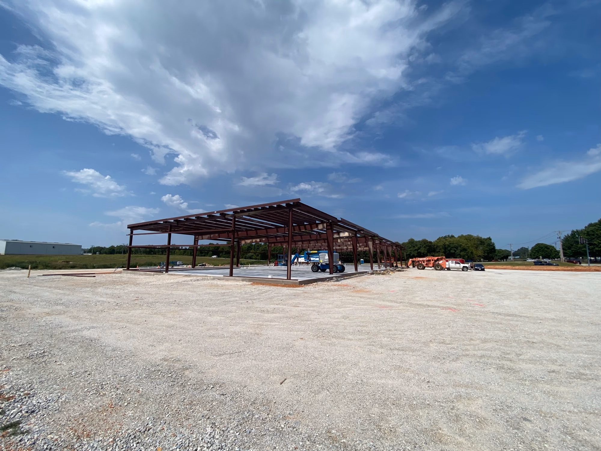 Structural steel columns and beams standing on the slab, seen from the open end of the building