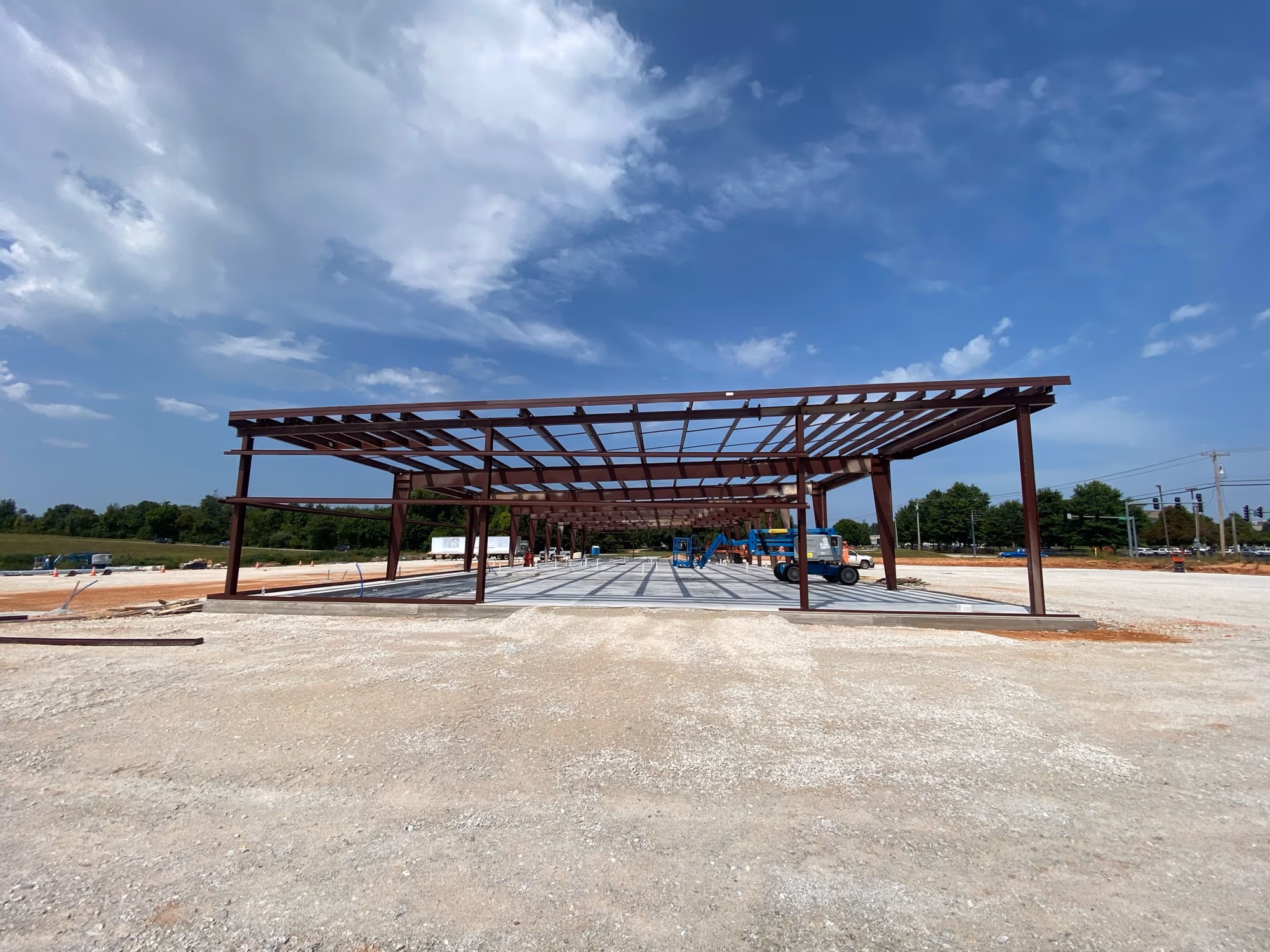 The steel frame from outside, with the full height and roof pitch of the building visible against the sky