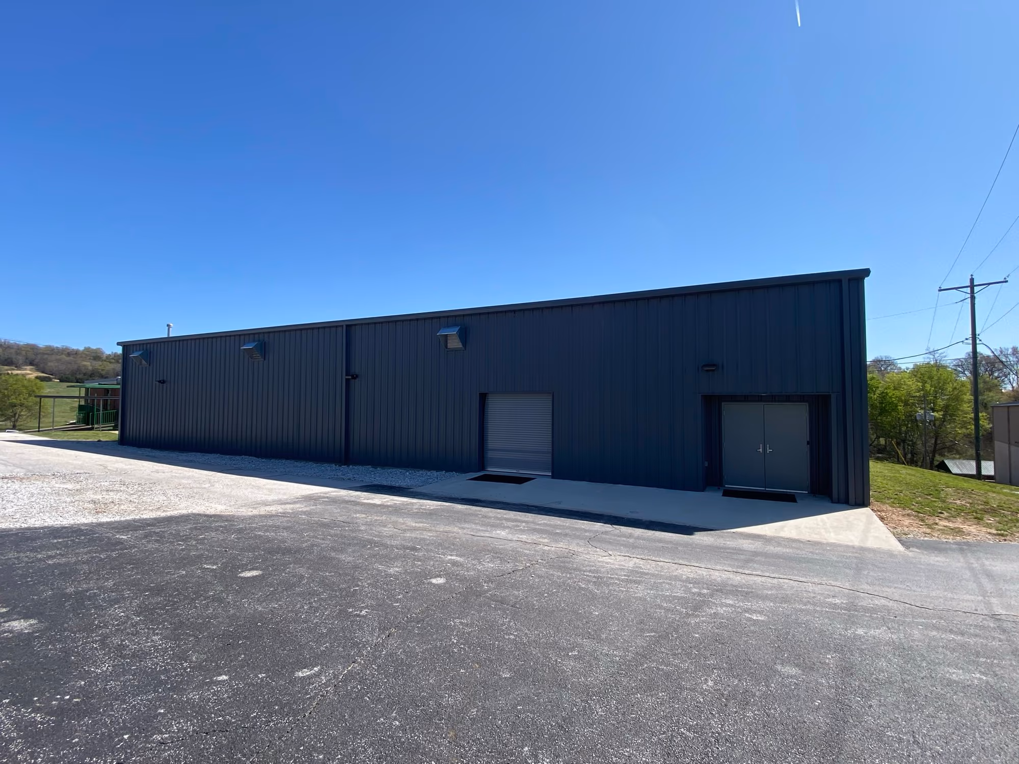 The Valley Springs Fitness Center — a charcoal red-iron metal building with a roll-up service door and double entry doors, seen from the paved lot