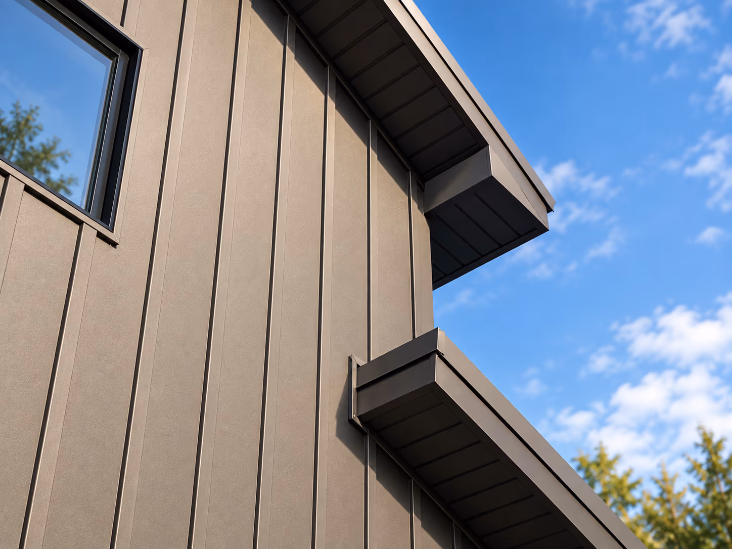 Close-up of bronze vertical standing-seam metal siding with a matching metal roof edge and soffit overhang against a blue sky